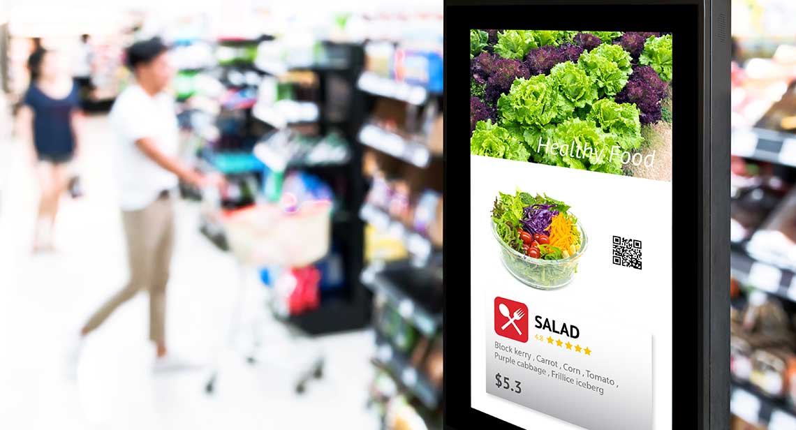 A digital display in a grocery store showing a salad advertisement with images of leafy greens and a bowl of salad.